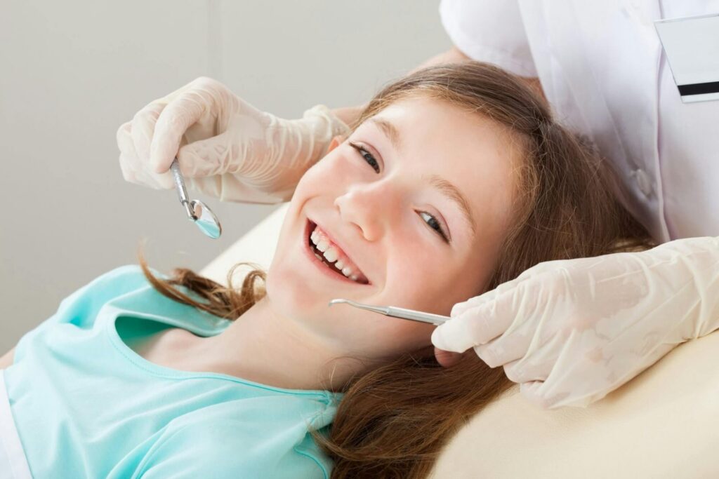 girl getting a dental sealant consultation smiling while on dentist chair